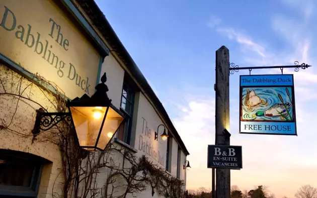 The outside of a Norfolk Pub with a sunset background