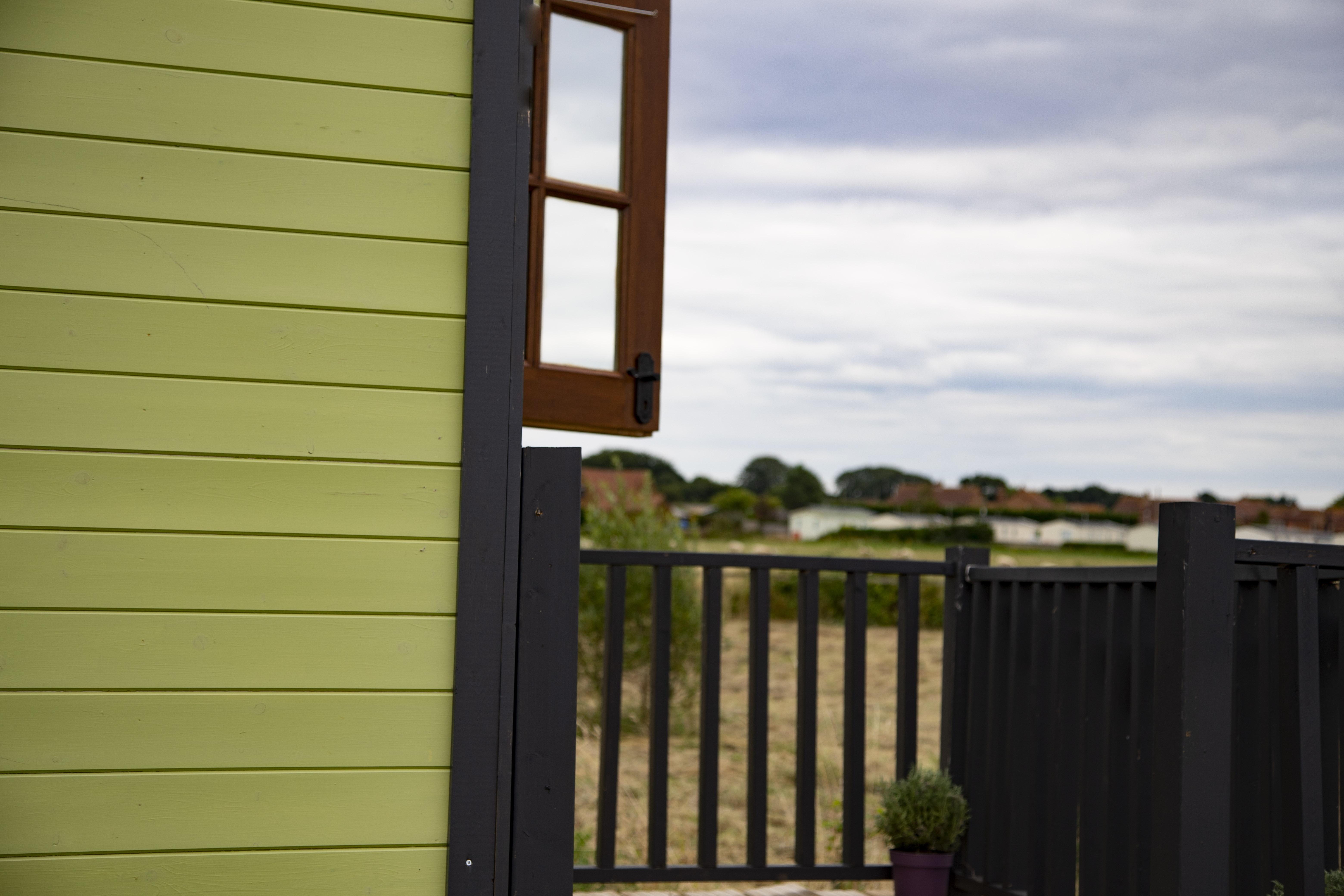 side of shepherds hut with an open window looking out on a field