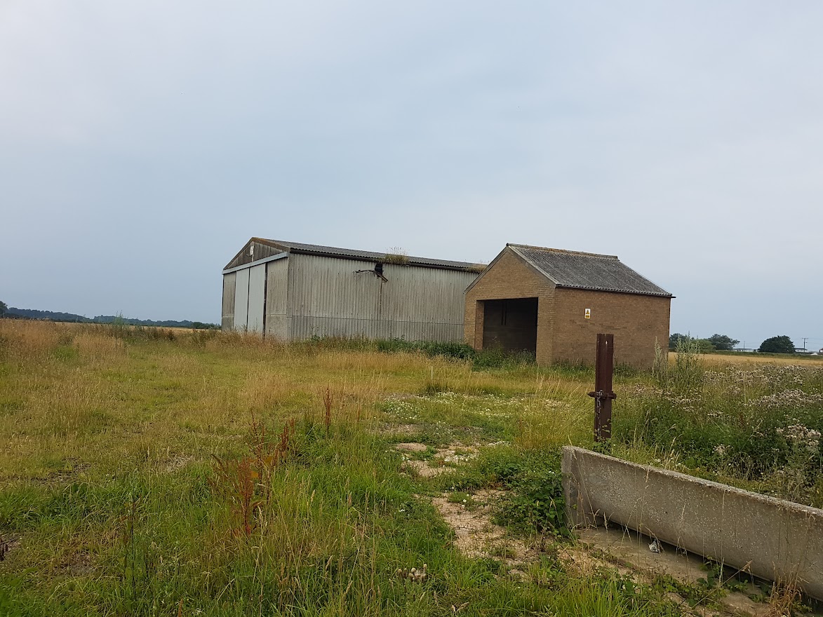 Two isolated outbuildings in a field