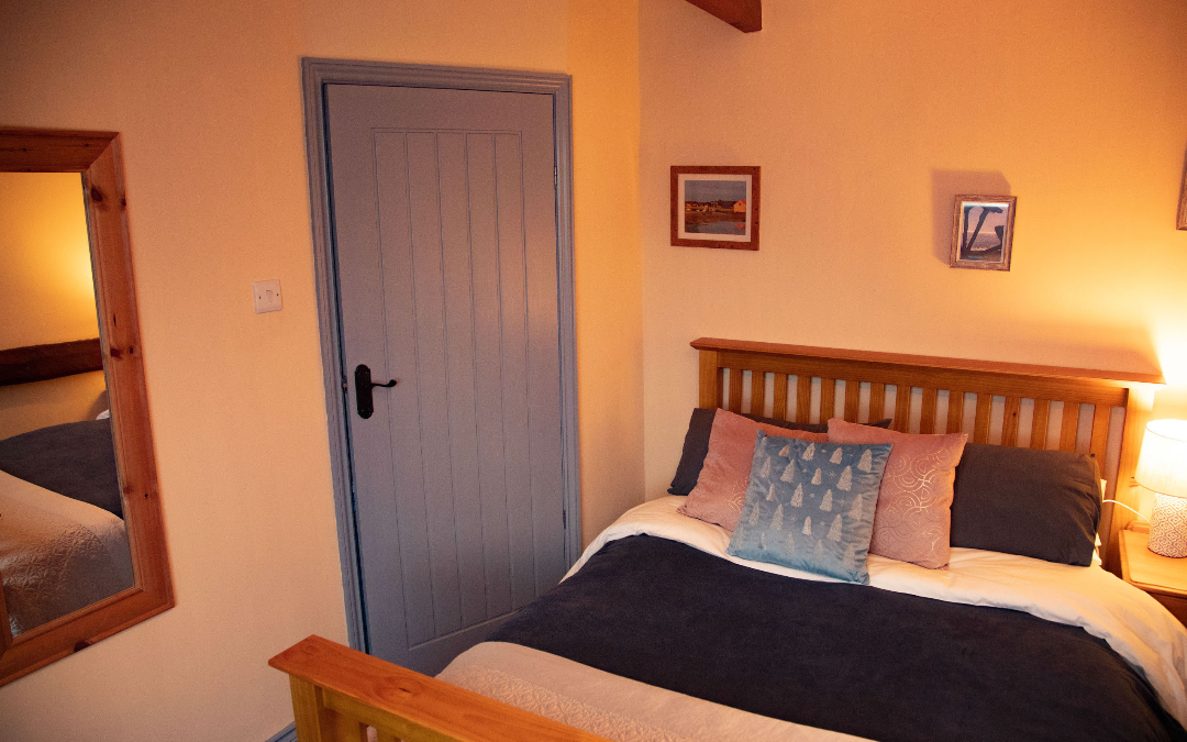 Norfolk Coastal Cottages, The Old Barn master bedroom with large comfy double bed and country wooden doors