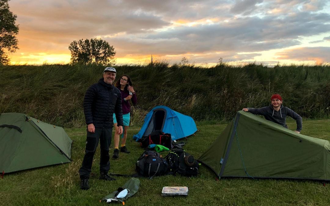 family camping in separate hikers tents as the sun sets