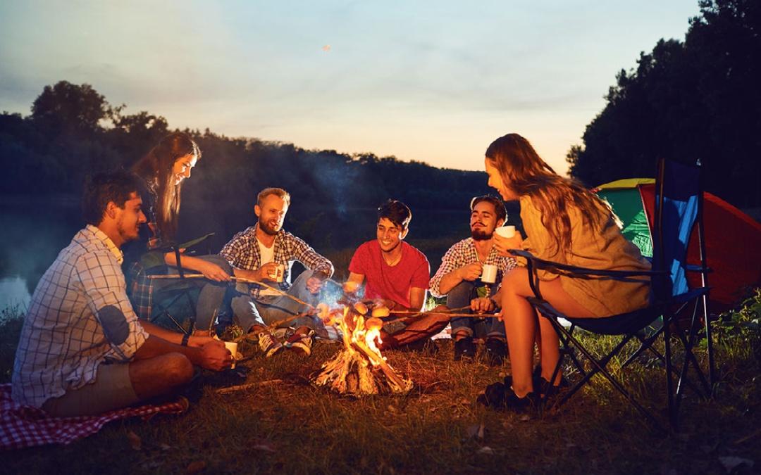 friends sitting around a campfire fire pit roasting marshmallows