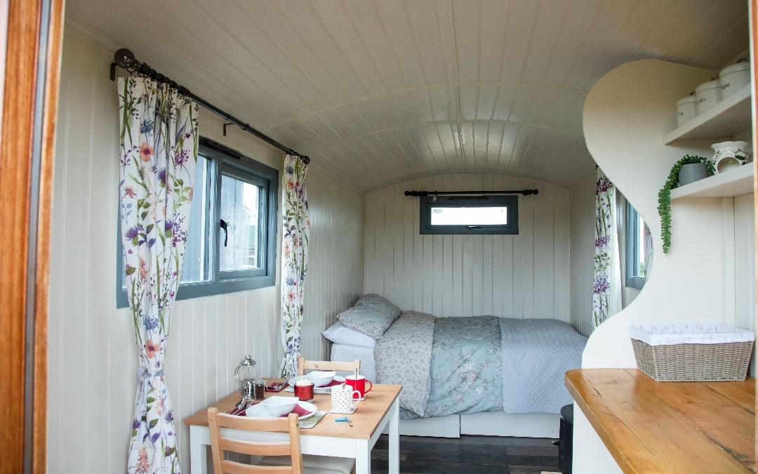 inside view of the comfy double bed and bistro seating in our glamping shepherds huts