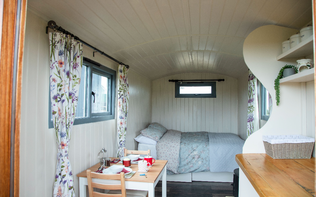 A view of the comfy double beds in our glamping shepherds huts, with bistro seating, perfect for couples