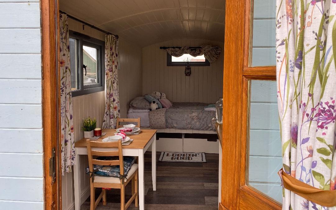 Inside our glamping shepherds huts, comfy double bed and bistro seating for couples