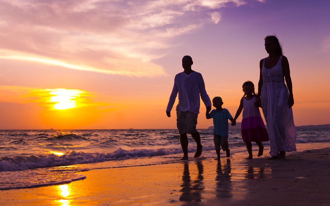 family on the beach as the sun sets over the sea