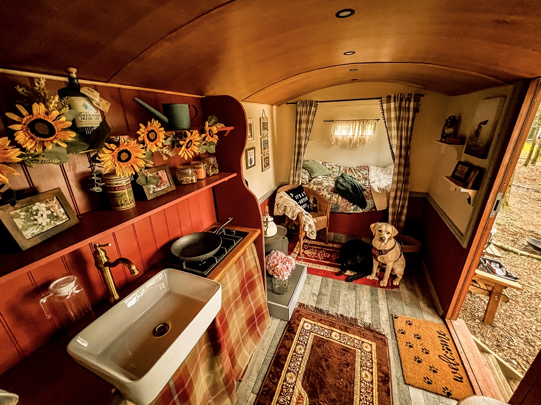 shepherds hut interior with made bed and wood burner