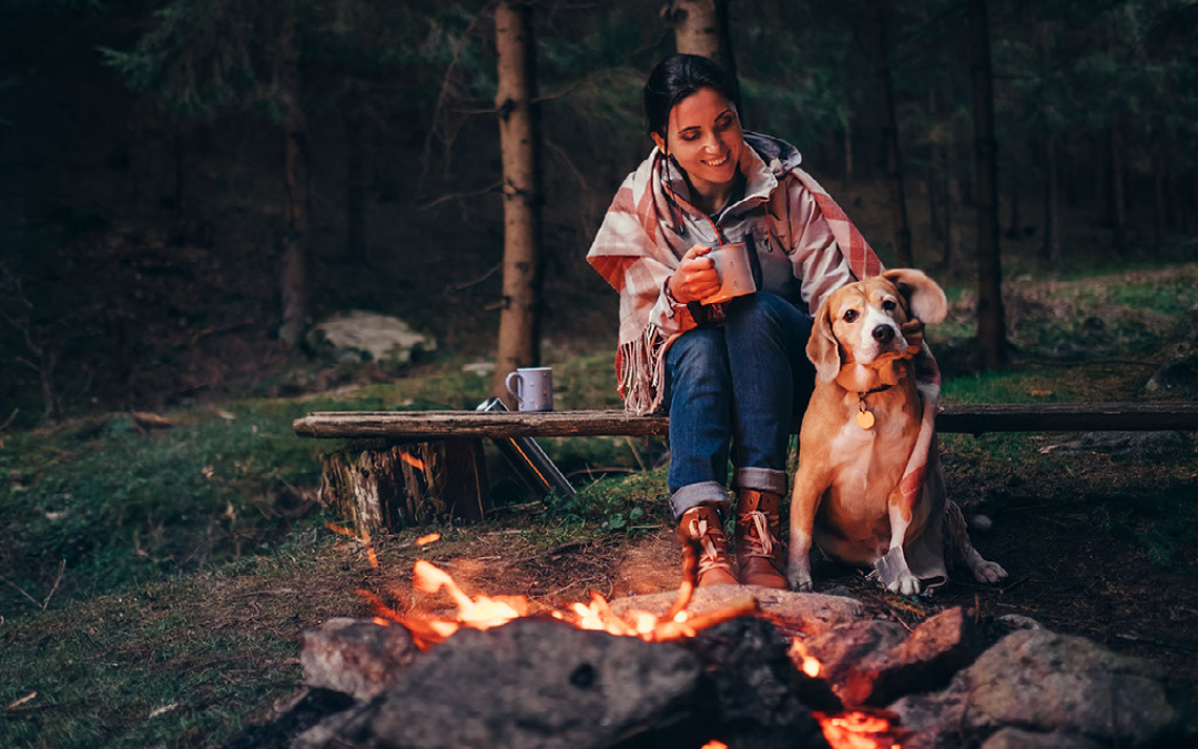 woman and dog sitting at a campfire