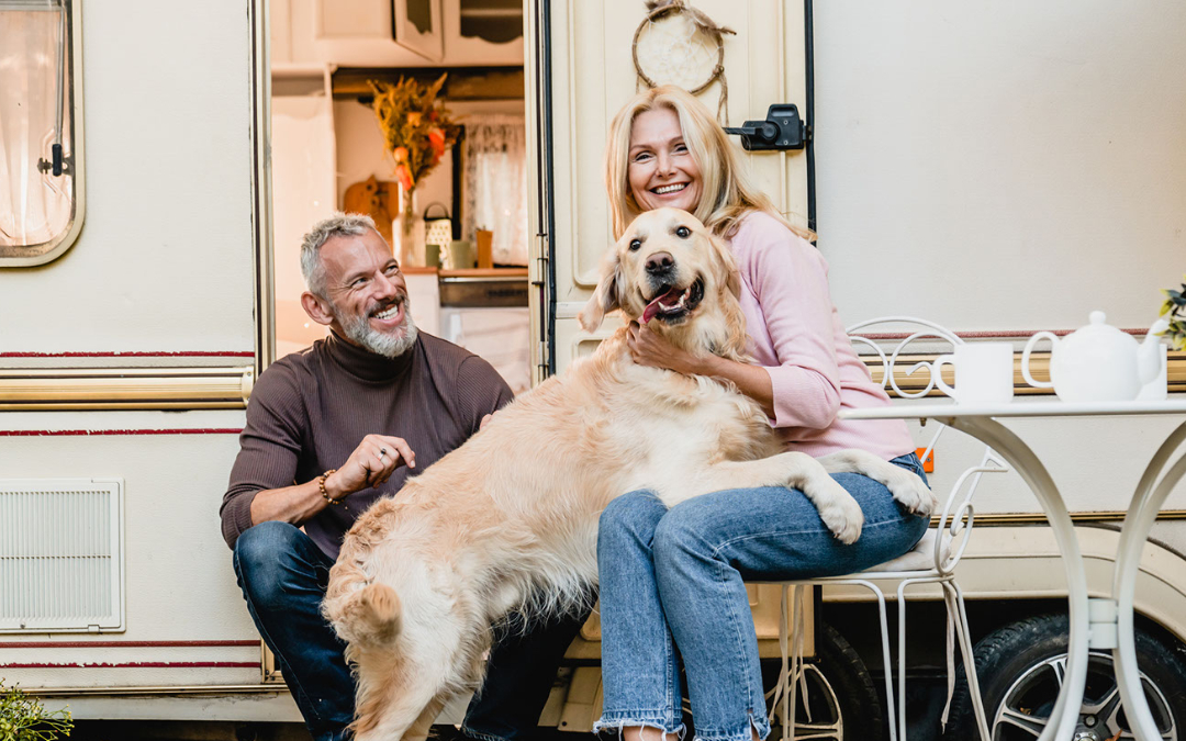 a couple outside a caravan with a dog