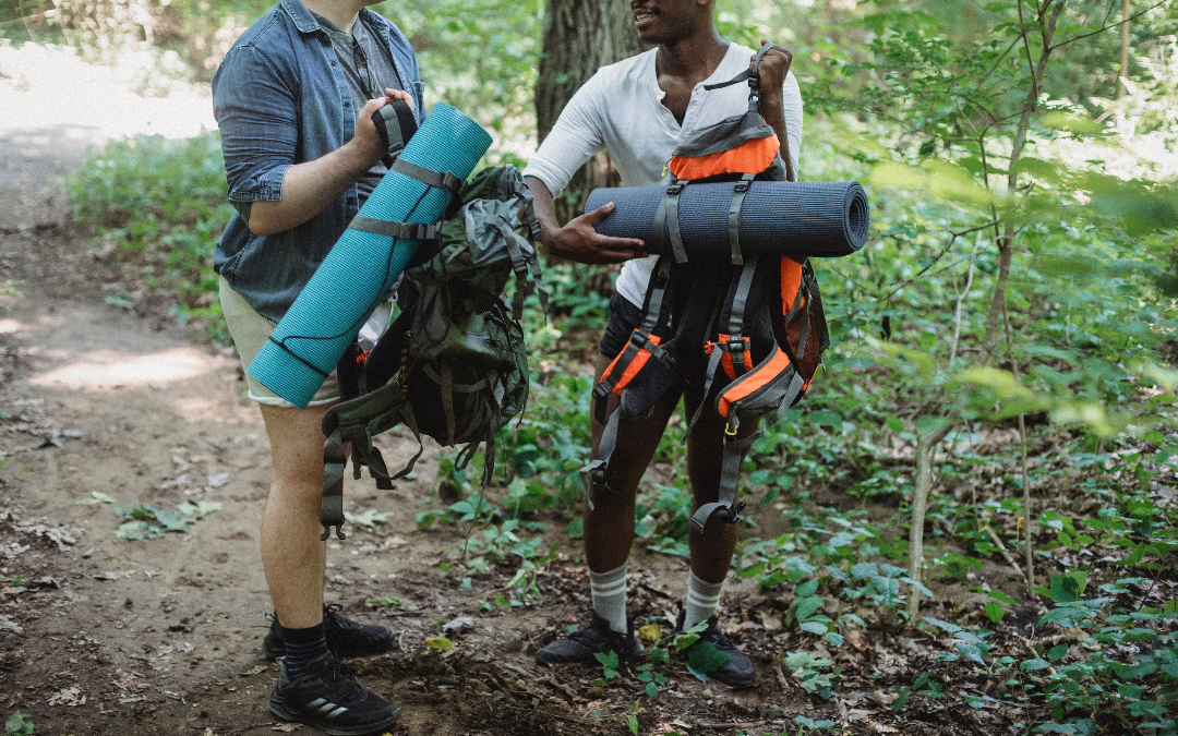 two people hiking in a forest with backpacks