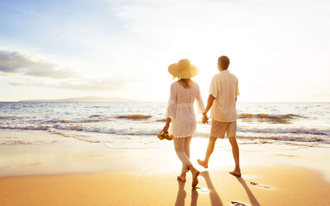 couple walking down beach at sunset