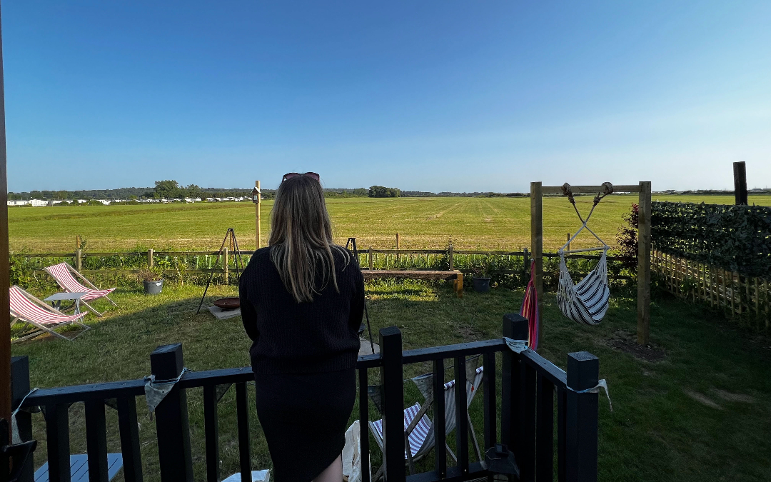 woman on a shepherd hut patio looking out over a field