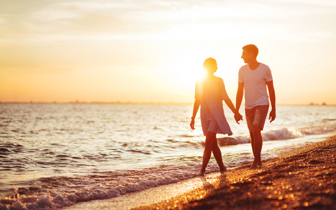 couple walking down beach at sunset