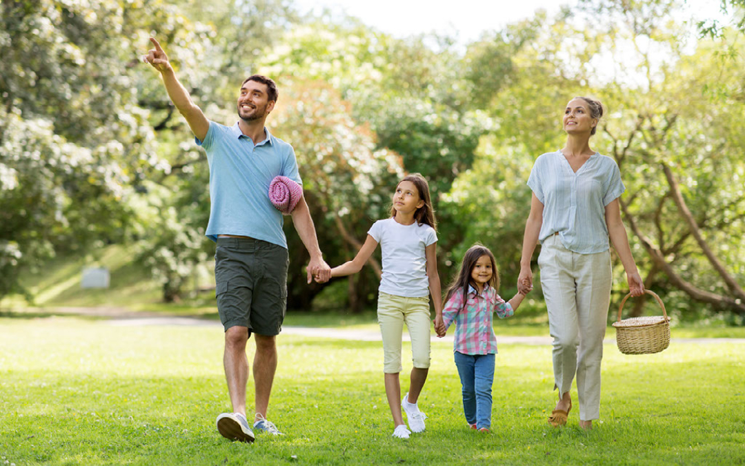 family walking through a grassy park with picnic