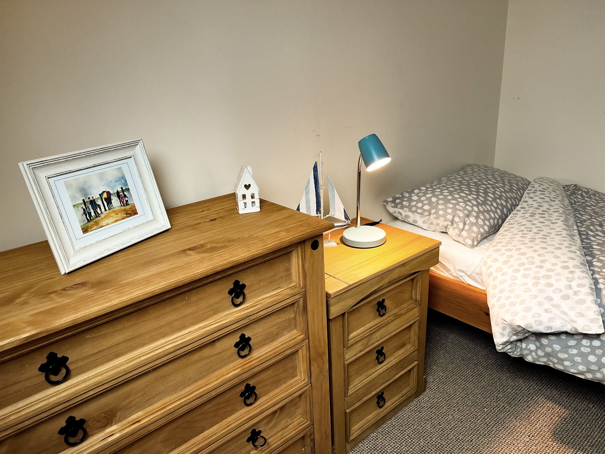 A single bed next to two chests of drawers