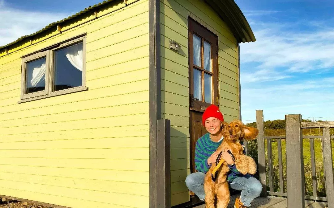 a person with their dog outside of a shepherd hut