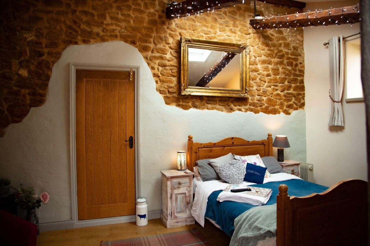 Double bed against a rustic wall with a door that leads into the Old Barn