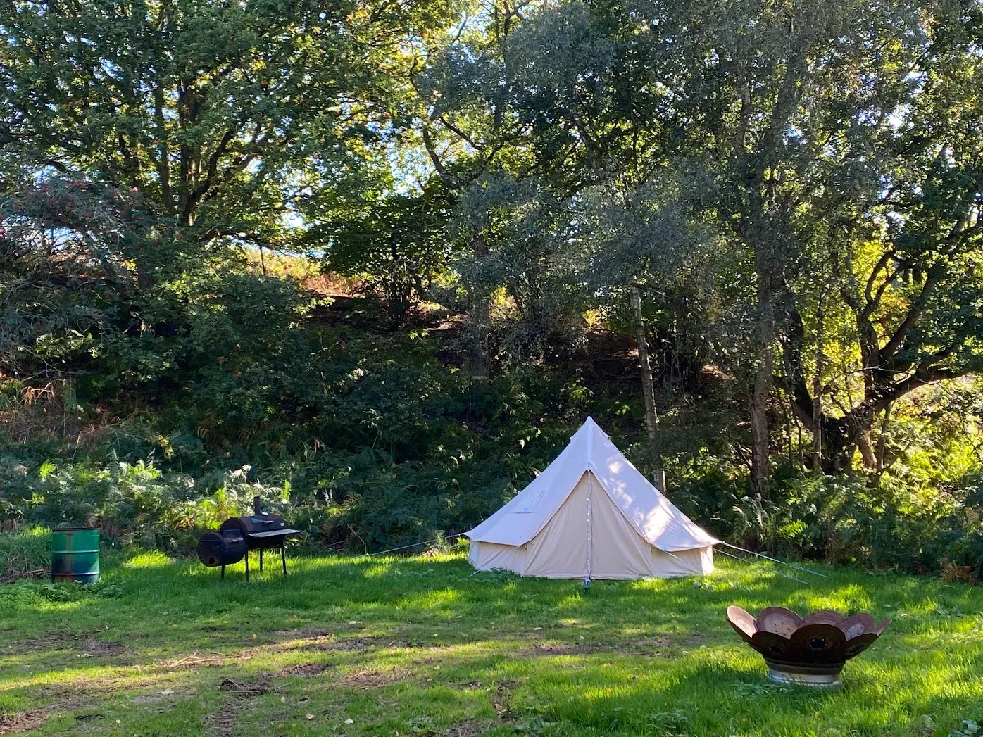 A bell tent with an outdoor bbq, firepit and plenty of green space