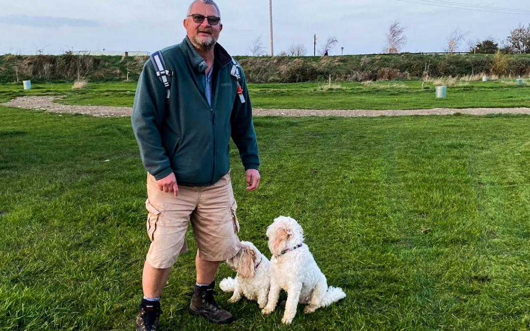 a happy guest in the campsite field with two dogs