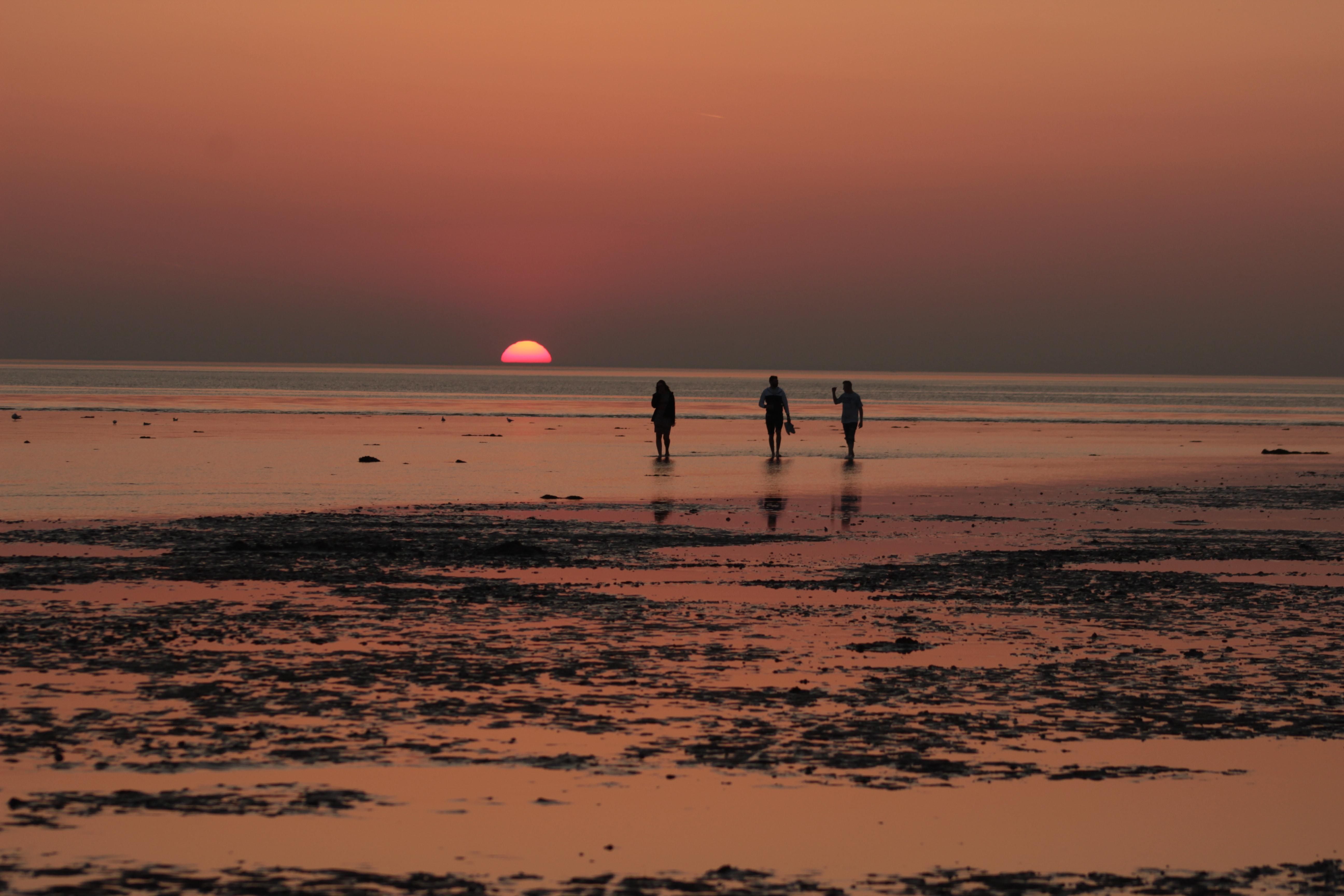 Sunsetting over the Norfolk Coast with friends walking along the sand in the red and orange glow