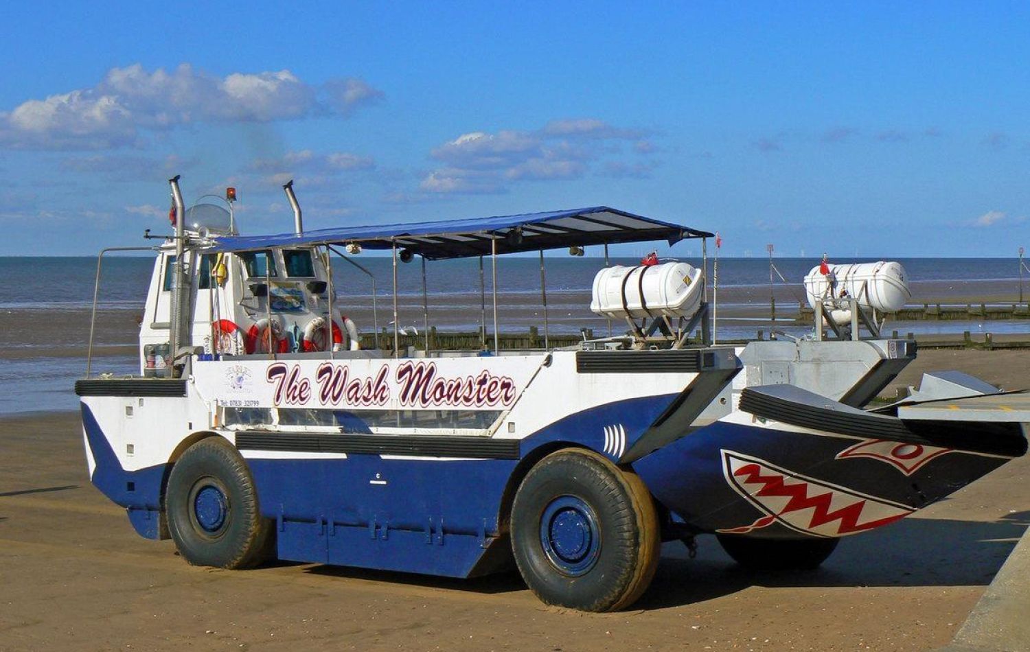 wiley the wash monster, an amphibious transport vehicle painted to have shark-like features, parked on the beach