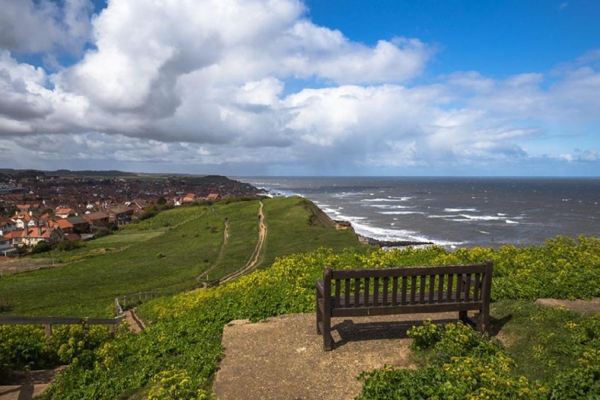 clifftop path out from sheringham with a bench looking over it