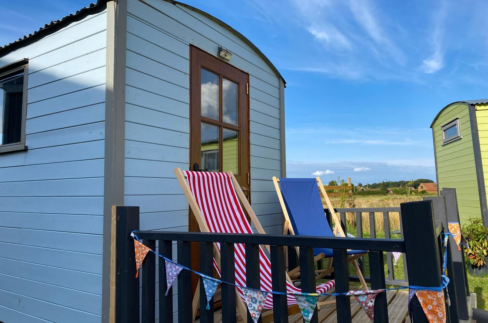 Shepherds Hut with two deck chairs outside and an open field in the background