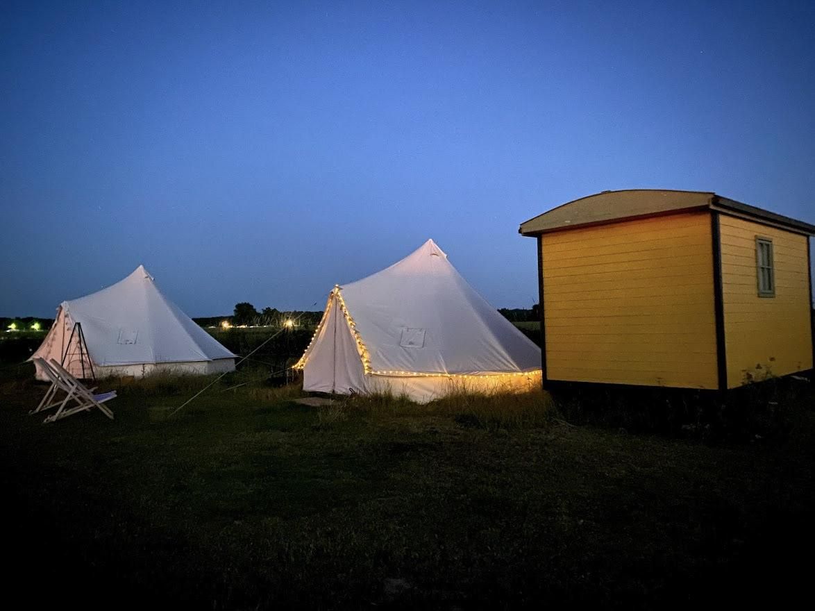 two bell tents and a shepherds hut lit up with fairy lights