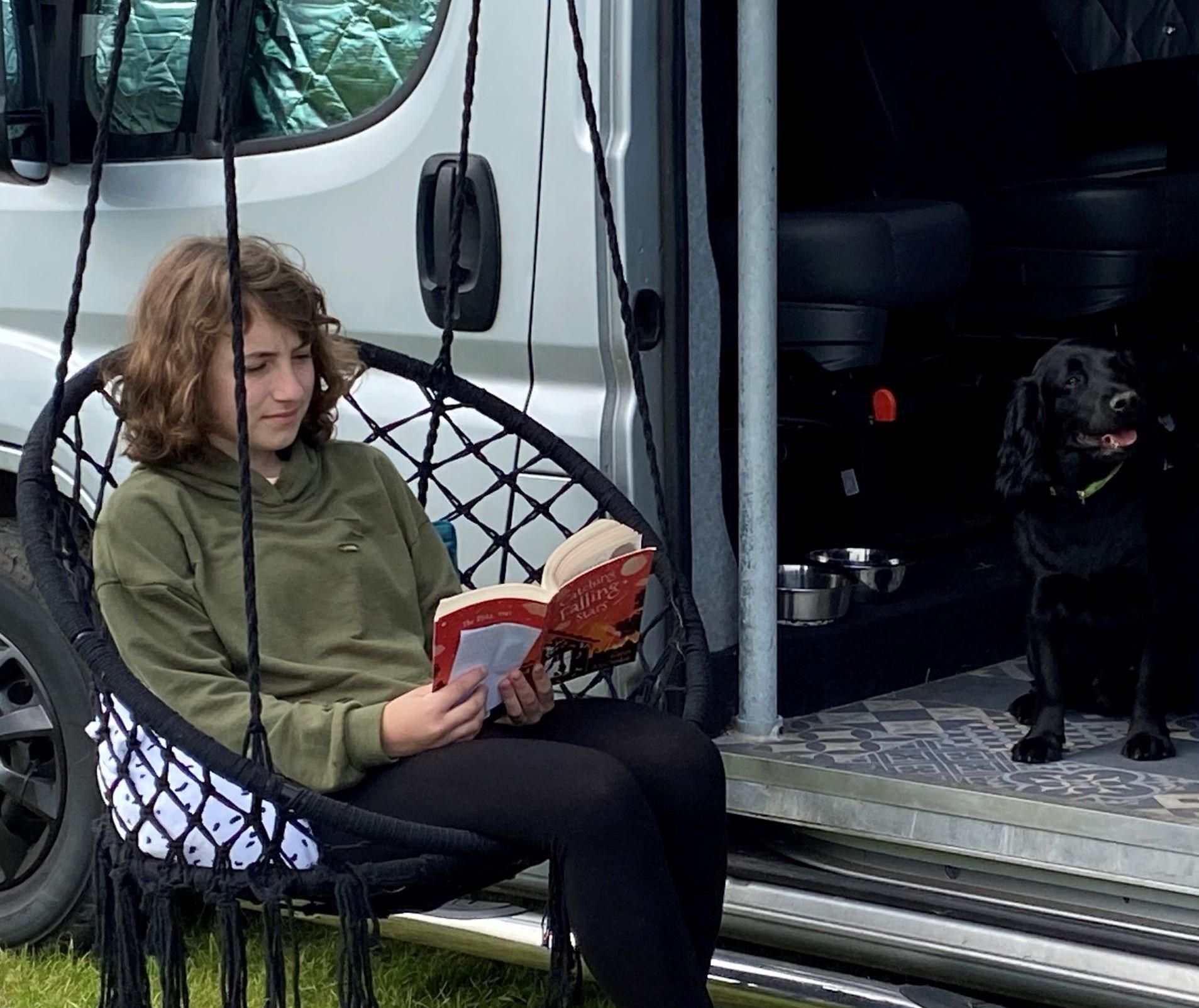 Camping hunstanton: A girl reading a book next to a motorhome