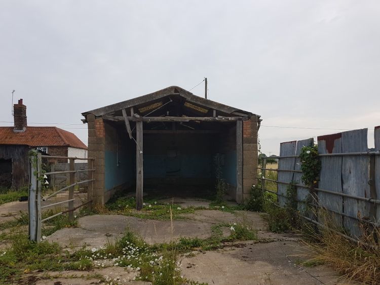 A cow shed that is empty and sagging