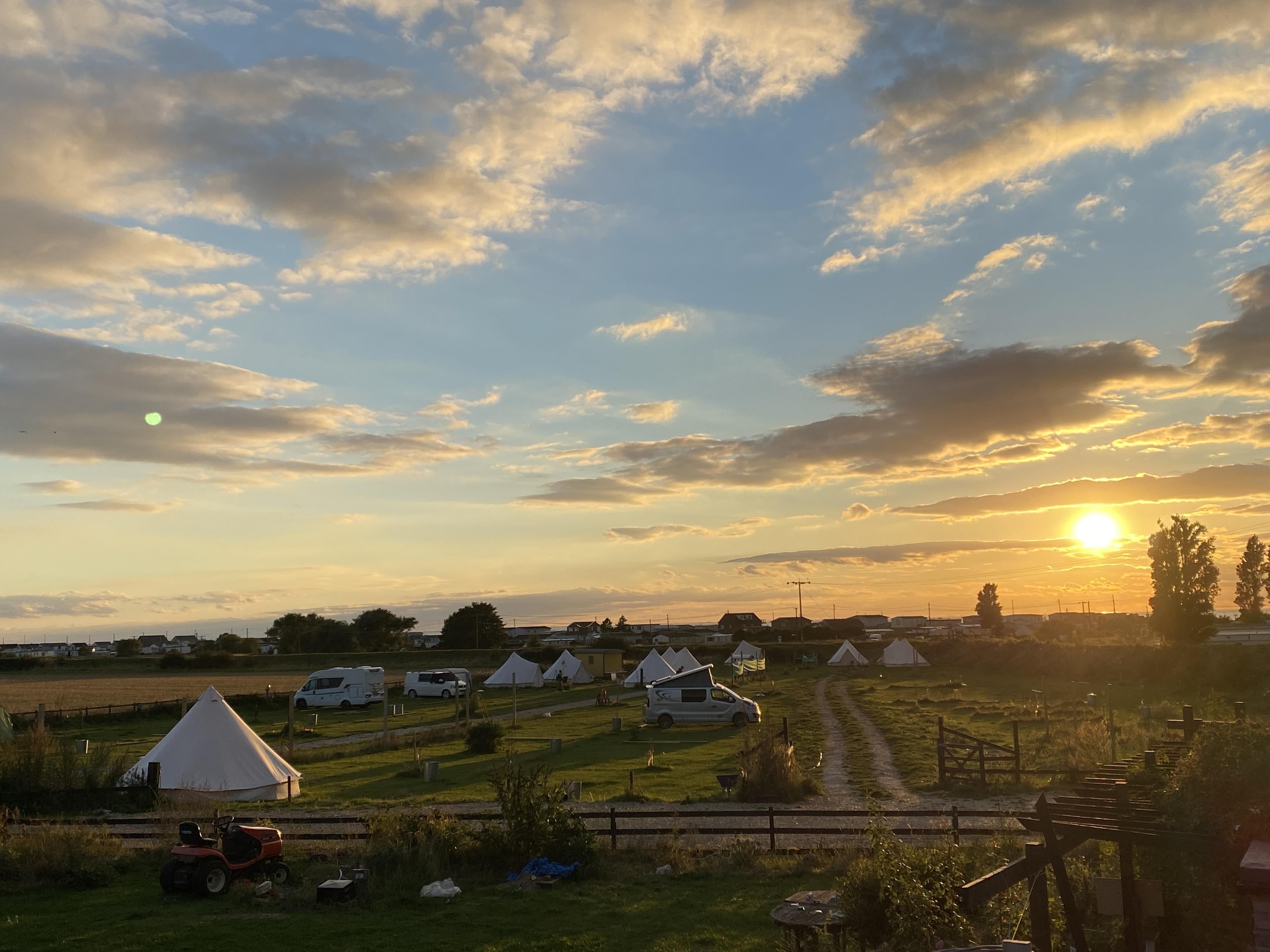 A campsite with the sun setting in the background with a beautiful blue sky