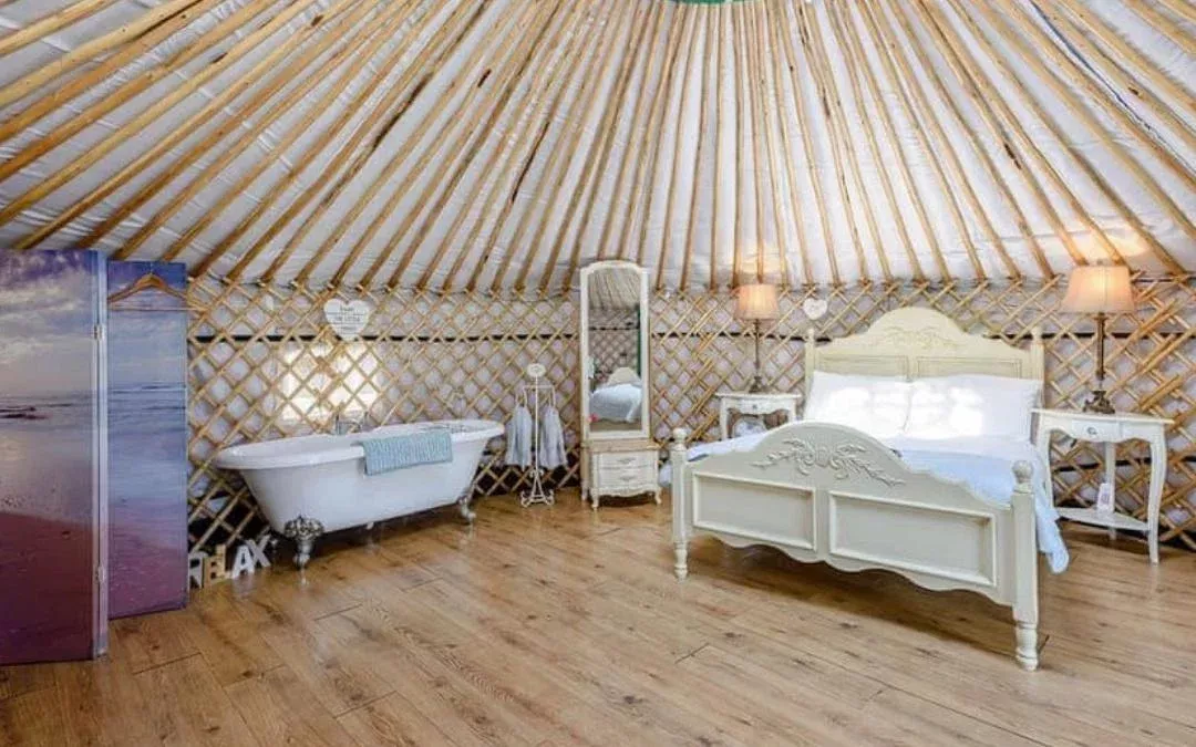 Inside a glamping yurt boasting a bath, a queen bed and other decor