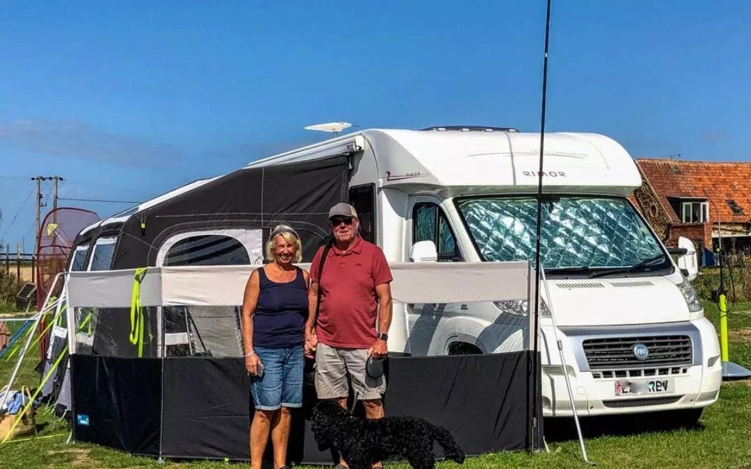 a couple with their dog outside their moterhome with awning set up