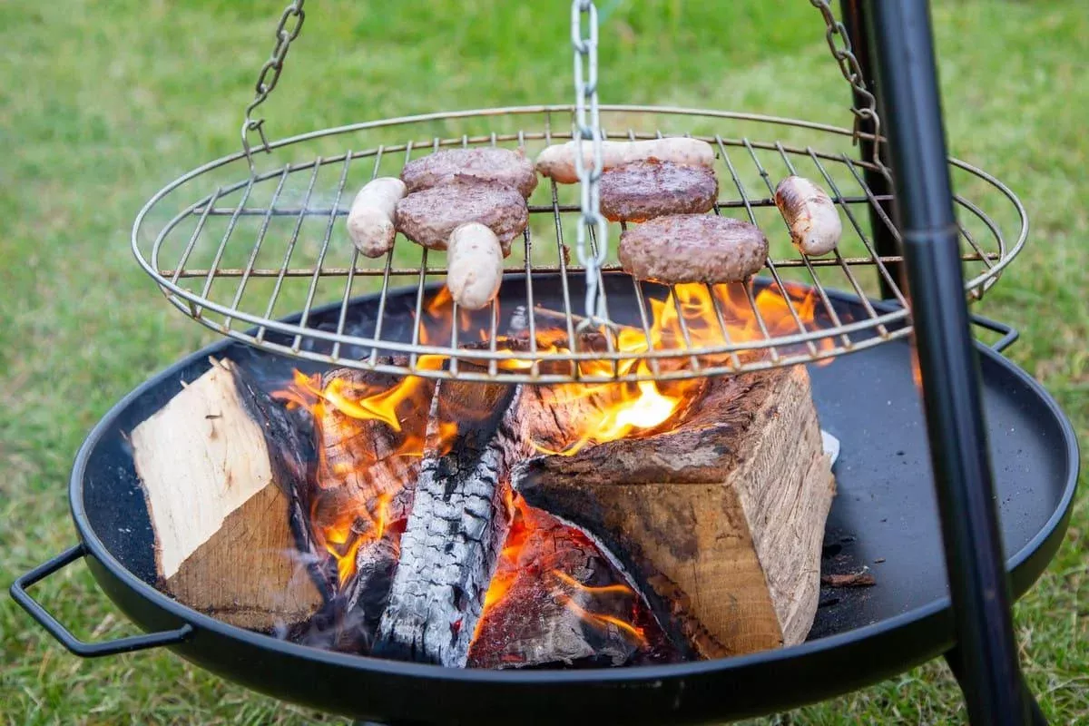 a wood fired campfire with burgers and sausages cooking