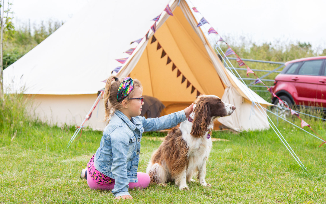 young girl petting dog at bell tent