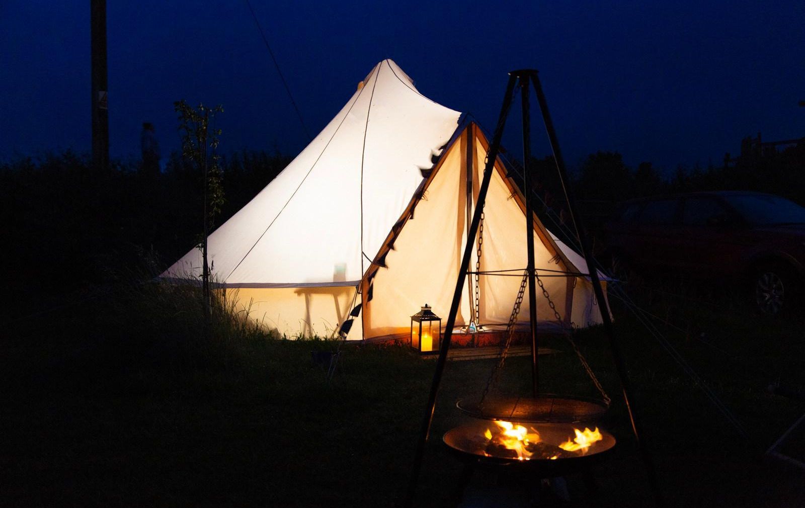 Bell tent at night with lit fire pit outside