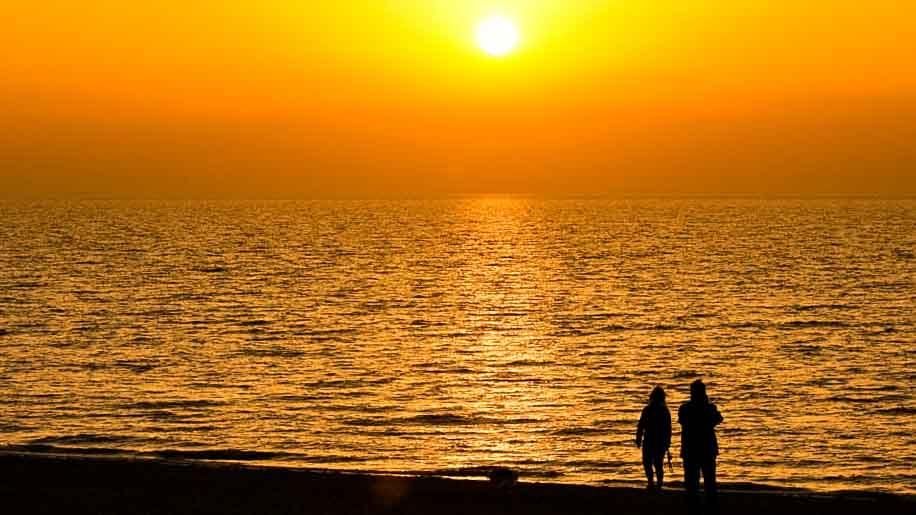 A couple enjoying a sunset walk on the beach
