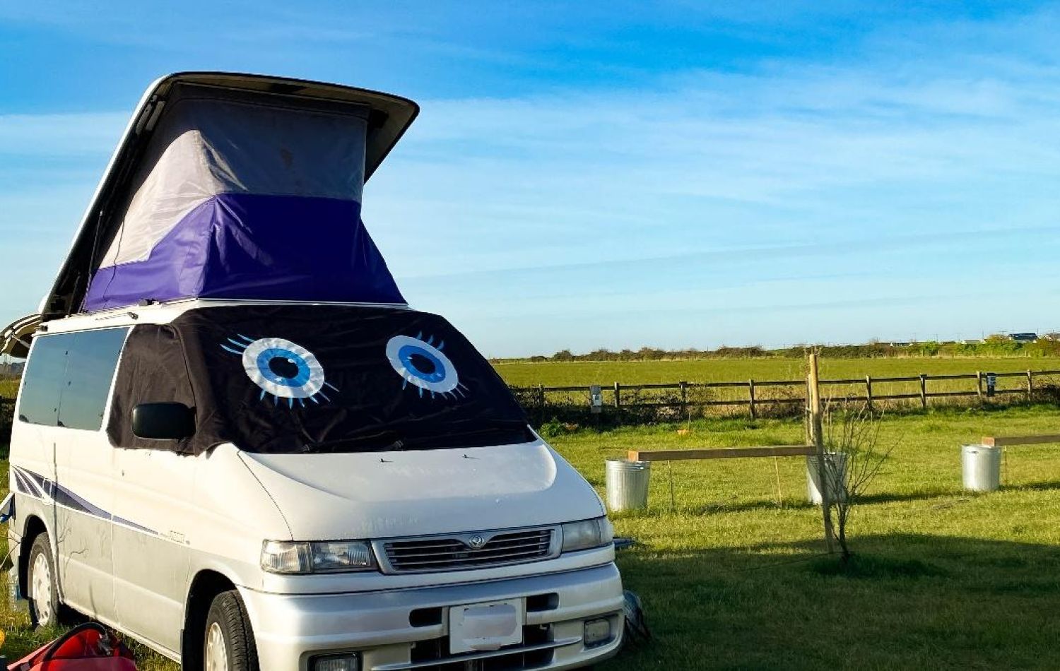 Campervan with roof tent basking in sunshine on a field