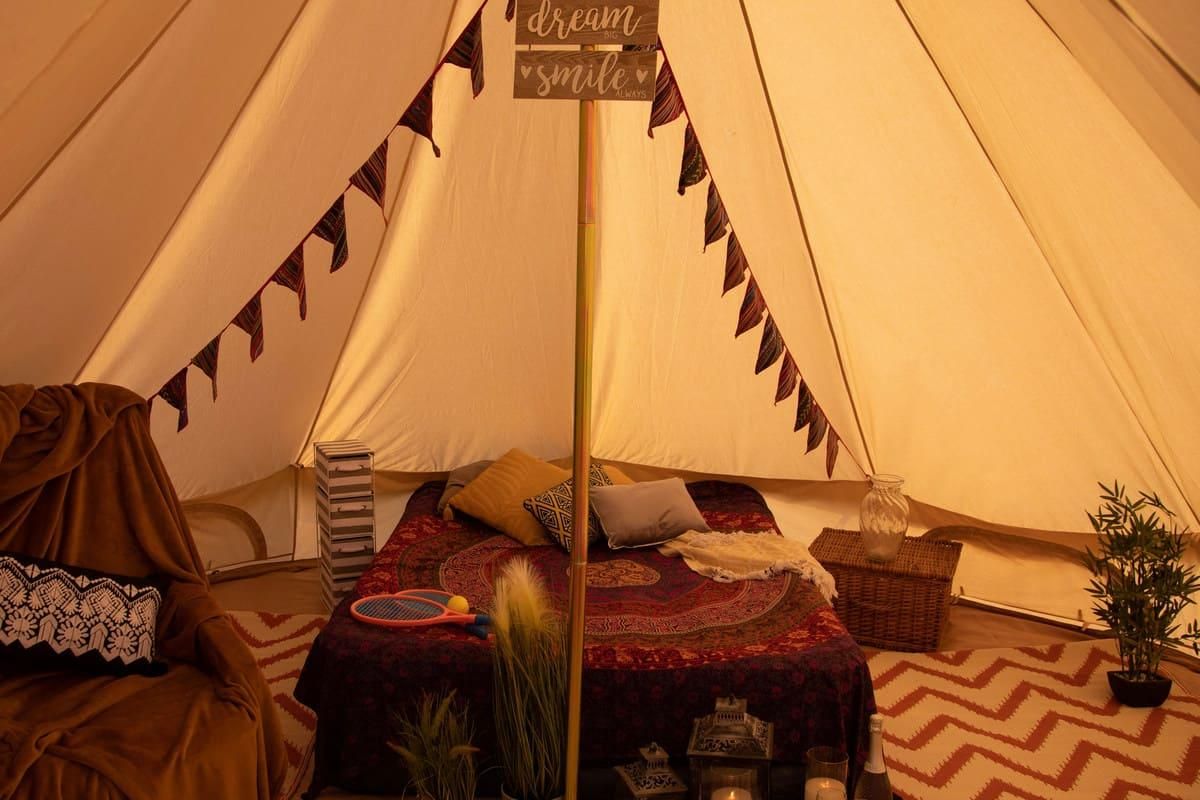Double bed inside bell tent surrounded by rustic furnishings
