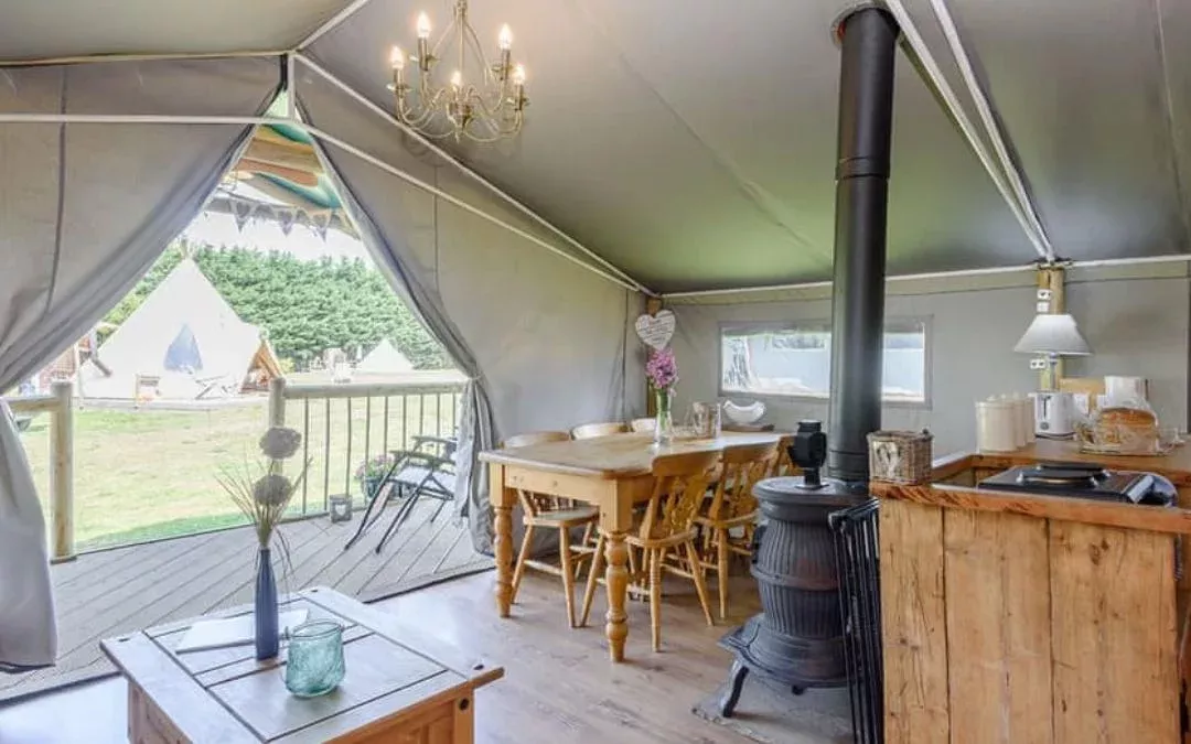 inside a safari tent with a fire, indoor seating and a kitchen