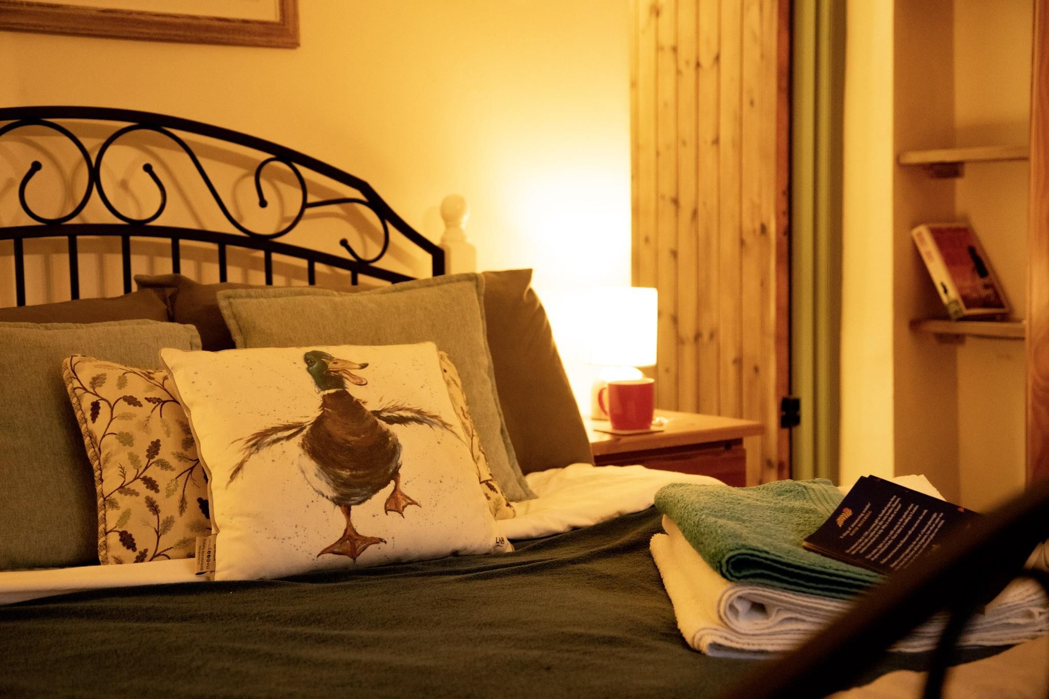 A made bed with towels atop basking in a warm glow