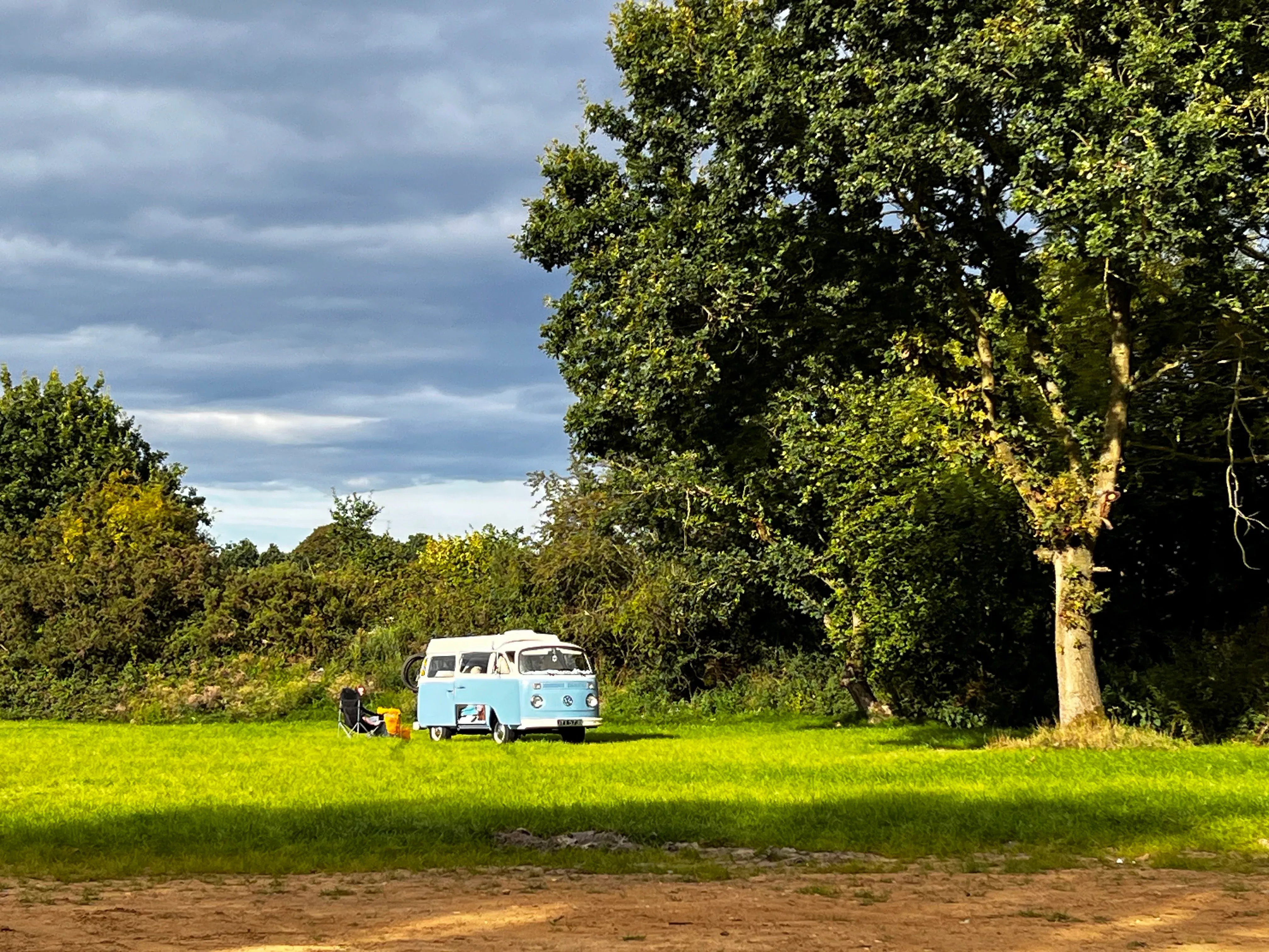 a light blue campervan pitched up on a campsite