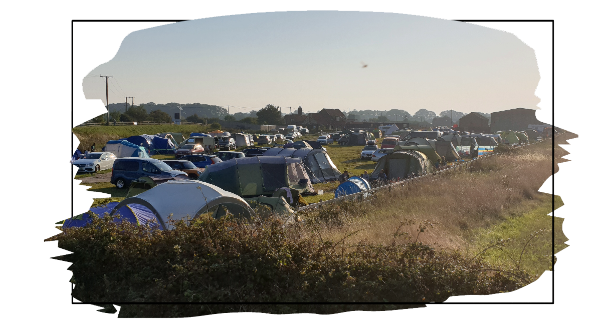 a campsite with many tents pitched on a sunny day on the Norfolk coast